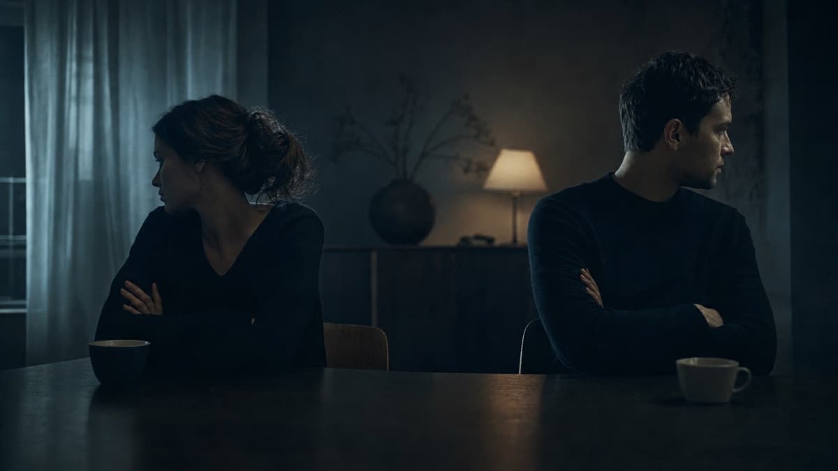 A couple at opposite ends of a table, facing away from each other
