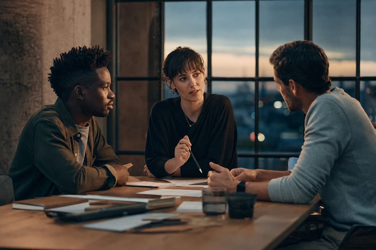 Three colleagues collaborating at a table at dusk